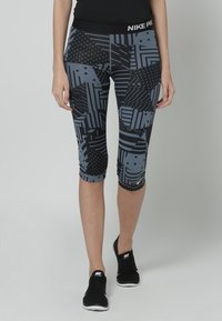 Legginsy Nike Pro w czarno-szarym geometrycznym wzorze, z różnorodnymi teksturami i wzorami, w tym paskami i kropkami.