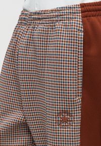 Καρό φόρμα από βαμβακερό μείγμα, με καφέ και μπλε μοτίβο, στερεή καφέ πλαϊνή ταινία και κεντημένη λεπτομέρεια λογότυπου αστεριού.