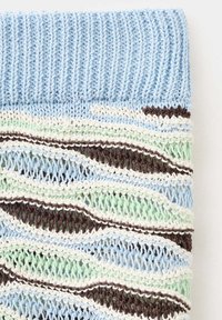 Tissu tricoté avec un bord-côte bleu clair et un motif ajouré multicolore en rayures bleues, vertes, marron et blanches.