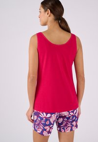 Roze katoenen tanktop met een gegolfde halslijn, gecombineerd met blauwe shorts met een wit bladerenpatroon. Eenvoudig, casual ontwerp.