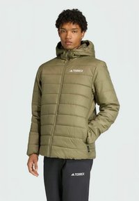 Olívazöld puffdzseki kapucnival, steppelt dizájnnal, elülső cipzárral és fehér TEREX logóval a bal mellrészen.