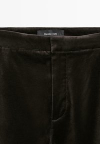 Zwarte fluwelen broeken met een gladde textuur, voorzien van een zijzak en een label met de tekst "Massimo Dutti" op de tailleband.