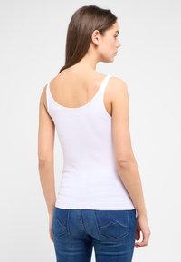Witte tanktop van ribstof, met smalle bandjes en een ronde halslijn, gecombineerd met blauwe denim jeans met achterzakken.