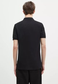 Polo shirt nera con maniche corte e colletto classico, texture liscia, realizzata in tessuto traspirante, design minimalista, senza loghi visibili.