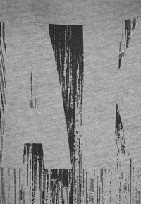 Textil gris con gran texto negro en un efecto de pincelada desgastado. El patrón tiene una apariencia texturizada con opacidades variadas.