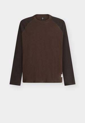 Long-sleeve crew neck shirt with dark brown body and black sleeves, featuring a small white label on the lower hem.