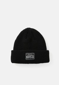 Black knitted beanie with a textured pattern and a folded cuff. Features a rectangular logo patch with "Vertere Berlin" text in white.