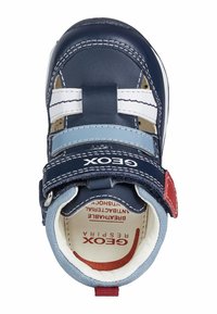 Zapato de cuero navy con acentos en blanco y azul claro. Cuenta con una correa ajustable, forro suave y suela de goma. Marca Geox visible en el interior.