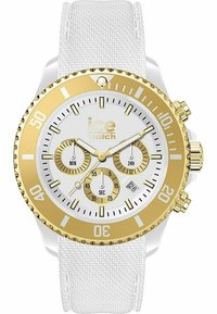Montre chronographe dorée et blanche avec un bracelet en silicone texturé blanc, un grand boîtier doré et un cadran blanc avec trois sous-cadrans et un affichage de la date.