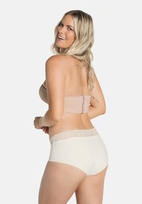 Nude strapless beha met gladde stof en achtersluiting; witte hipsteronderbroeken met kantafwerking bij de taille, zijaanzicht weergegeven.
