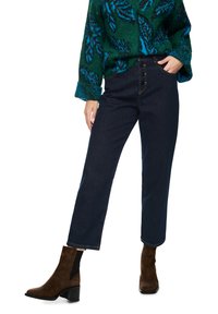 Dark blue high-waisted jeans with a straight leg and button fly. Worn with a green and blue leaf-patterned sweater and brown ankle boots.