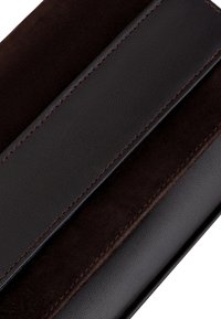 Portafoglio di pelle nera con finiture lisce e scamosciate, caratterizzato da cuciture marroni e un design elegante. Due sezioni visibili in una vista dall'alto.