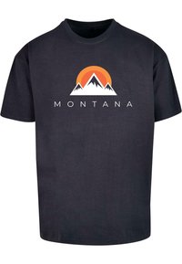 Zwart katoenen t-shirt met een grafisch ontwerp van bergen en een zonsondergang in oranje, wit en zwart; het woord "MONTANA" onder het ontwerp.