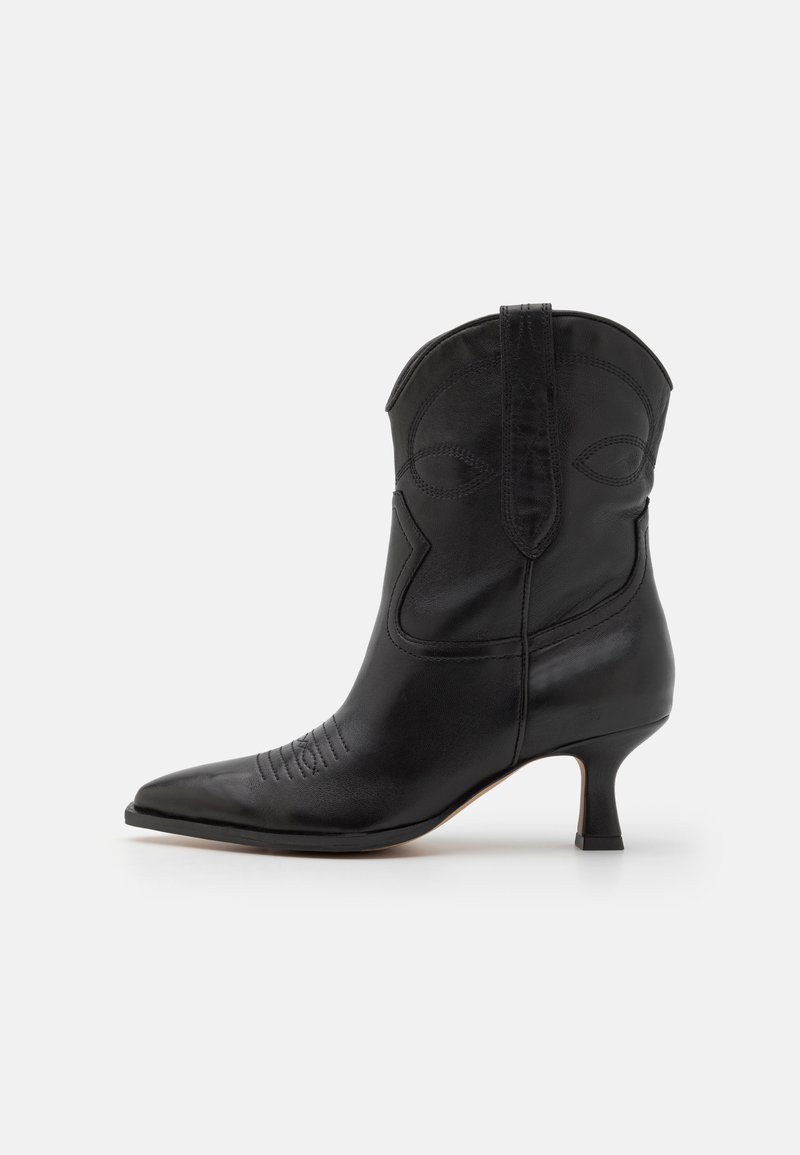 Bota cowboy de cuero negro con punta afilada, tacón bajo y costuras decorativas en el eje y en la zona de la punta. Textura suave en todo.