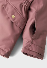 Pink waterproof fabric jacket sleeve featuring an elastic cuff, side pocket with a gold button, and a zipper detail on the seam.