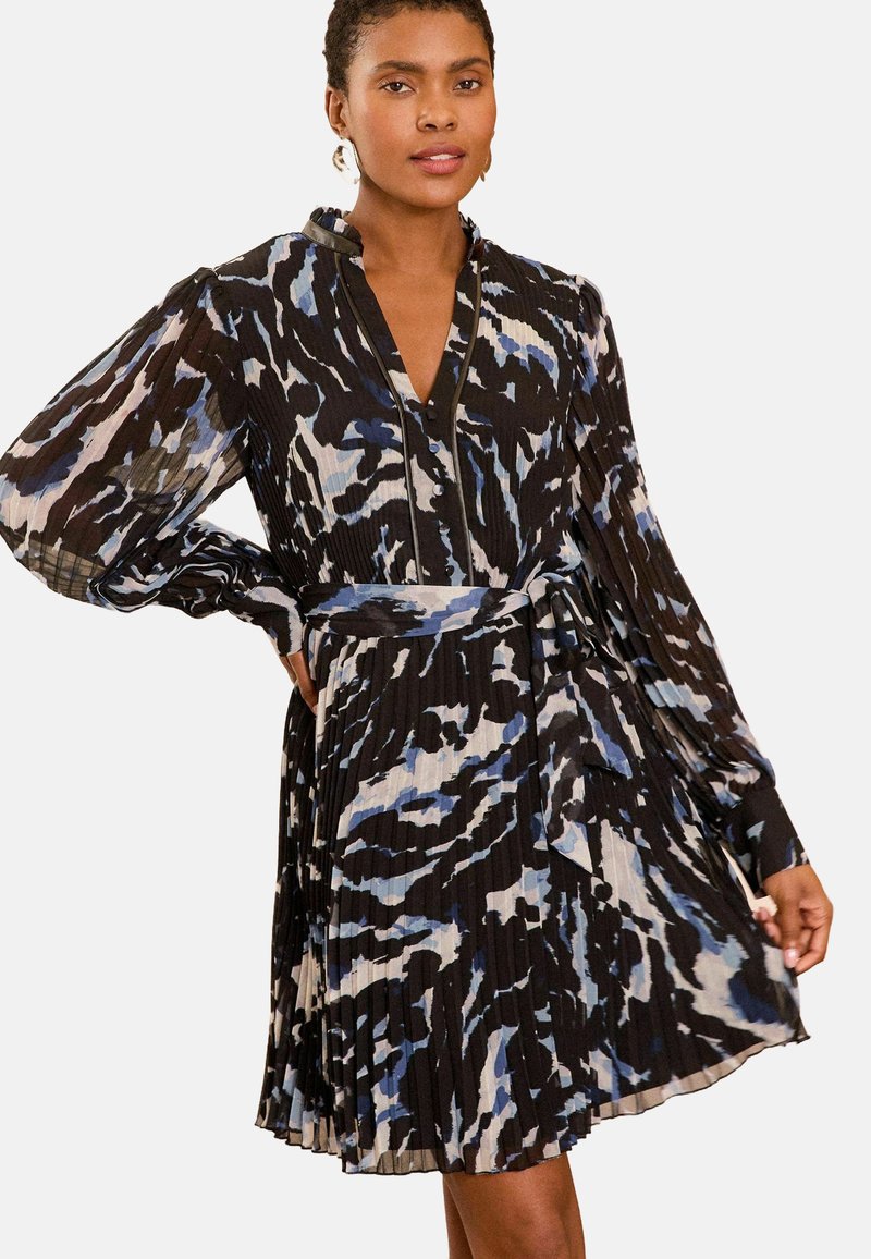 Juoda suknelė su plevėtota medžiaga, turinti mėlynus ir pilkus abstrakčius raštus, ilgos rankovės ir suderinta diržo detalė. V formos iškirpė ir tekstūruota detalė.