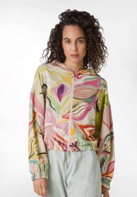 Giacca con cappuccio e zip in tessuto morbido con un motivo floreale colorato che presenta tonalità di rosa, verde e giallo. Vita e polsini elasticizzati.
