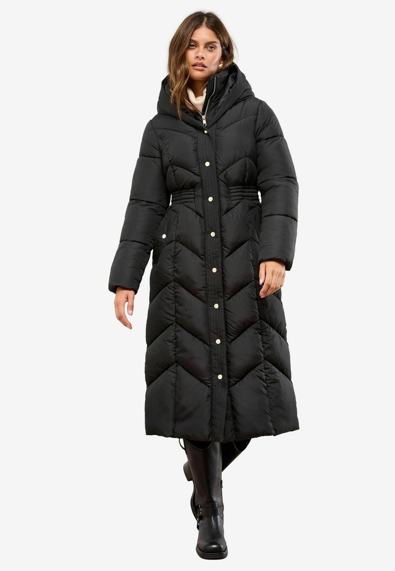 Cappotto puffo nero con design a chevron, lunghezza lunga, cappuccio e bottoni a pressione. Tessuto testurizzato, con tasche laterali e dettaglio in vita elasticizzato.