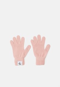 Strikkede hansker i myk rosa, med ribbestrikket mansjett og en liten etikett med logo på den ene hansken. Hver hanske har fem fingre.