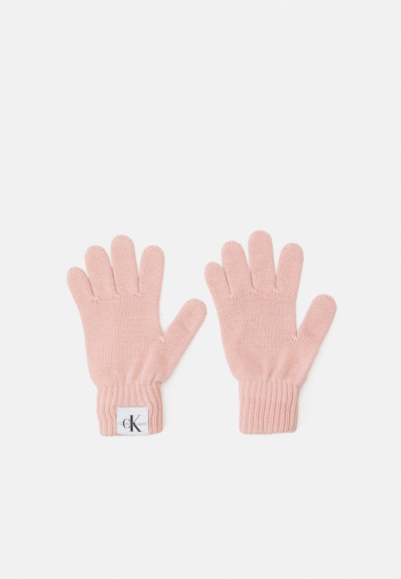 Strikkede hansker i myk rosa, med ribbestrikket mansjett og en liten etikett med logo på den ene hansken. Hver hanske har fem fingre.