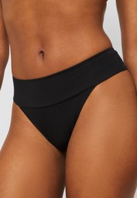 Black high-waisted bikini bottom, smooth texture, minimal stitching, fitted design, showcasing a curved waistband and medium leg cut.