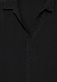 Schwarzes kurzärmliges Hemd aus strukturiertem Stoff, mit einem V-Ausschnitt und dezenten Nähten am Kragen und der Knopfleiste.