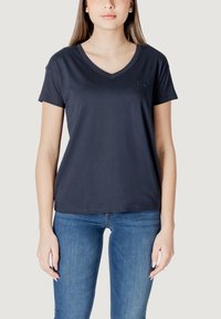 T-shirt blu navy a collo a V realizzata in morbido cotone, con maniche corte e un piccolo logo del marchio sul lato sinistro del petto. Texture liscia, vestibilità regolare.