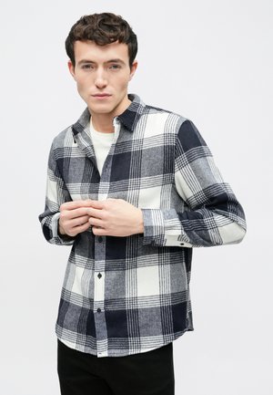 Męska koszula w kratę w kolorze granatowym i białym, wykonana z teksturowanego materiału, z zapięciem na guziki, kołnierzem w szpic i długimi rękawami.