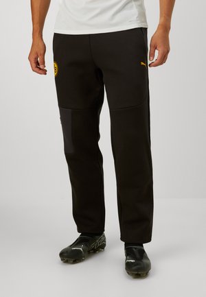 Pantalones deportivos negros con paneles laterales, logo de Puma y emblema del Borussia Dortmund. Confeccionados en tela texturizada, diseñados para comodidad y rendimiento.