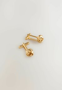 Goldene Manschettenknöpfe mit einem gewundenen Knotendesign, das glatte und gerippte Texturen aufweist. Die Form ist rund und länglich, mit einer polierten Oberfläche.