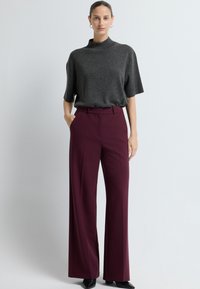 Szary, krótki top z wysokim dekoltem, połączony z szerokimi burgundowymi spodniami. Spodnie mają szlufki na pasek oraz boczne kieszenie.