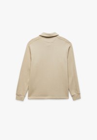 Beżowa longsleeve polo z miękkiego materiału, płaskim kołnierzykiem, ściągaczami przy mankietach oraz gładką fakturą. Prosty design bez wzorów czy akcentów.