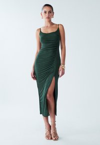 Grünes, gerafftes Kleid aus weichem Stoff mit geradem Ausschnitt, dünnen Trägern und hohem Seitenschlitz, kombiniert mit beigefarbenen, Riemchen-Heels.