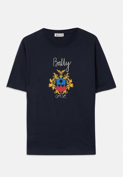 Tamsiai mėlynas medvilninis marškinėliai su spalvinga herbo grafika, kuriame pavaizduota erelis, apvalus dizainas ir tekstas „Bally Crest“ balta ir auksine akcentais.
