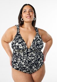 Costume da bagno a righe bianche e nere con scollatura a V profonda, spalline larghe e dettagli di tessuto arricciato. Tessuto liscio e forma aderente.