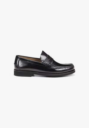 Zapato mocasín de cuero negro para hombre, sin cordones, con costura moc toe y tacón bajo, mostrado de lado sobre un fondo blanco.