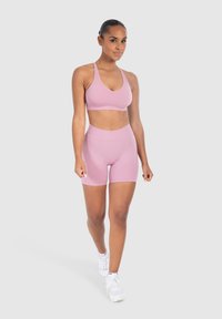 Lichte roze sportbeha en hoge taille shorts, gemaakt van gladde, rekbare stof. Het ontwerp heeft dunne bandjes en een aansluitende pasvorm.
