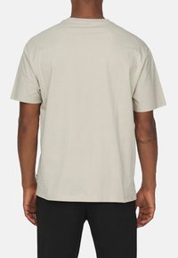 Helles graues T-Shirt mit kurzen Ärmeln aus Baumwolle, das einen lässigen Schnitt und ein sauberes, minimalistisches Design mit geradem Saum aufweist.