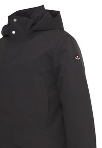 Giacca nera impermeabile con colletto alto, bottoni a pressione e una patch sulla manica. Presenta una texture liscia e tasche laterali.