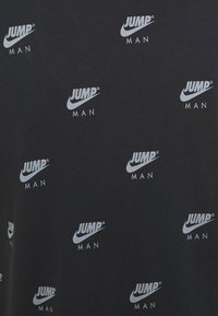 Černé tričko s opakovanými bílými nápisy "JUMP MAN" a logy Nike. Tkanina vypadá hladce a má klasický design kulatého výstřihu.