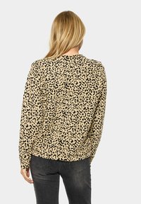 Felpa con stampa leopardata in beige e nero. Maniche lunghe, collo rotondo, vestibilità comoda, tessuto testurizzato, con orlo e polsini a costine.