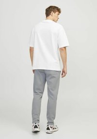 White short-sleeve t-shirt paired with gray sweatpants. The t-shirt features a classic cut, and the pants have a smooth texture and elastic cuffs.