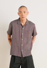 Short-sleeve, button-up shirt in multicolored striped pattern; features a pocket, folded collar, and textured fabric.