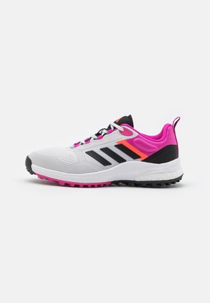 Chaussure de sport blanche et rose avec des rayures noires, un accent orange et une semelle texturée conçue pour les activités en extérieur.