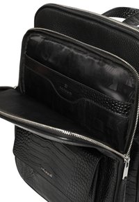 Czarna skórzana torba z teksturowanym wzorem skóry krokodyla, srebrnym zamkiem błyskawicznym oraz wieloma wewnętrznymi przegródkami wyściełanymi gładką czarną podszewką.