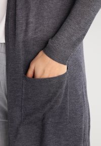 Cardigan grigio realizzato in morbido tessuto, con maniche lunghe, una tasca frontale e polsini a coste. Texture liscia con vestibilità comoda.