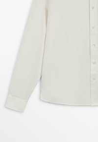 Biała koszula na guziki z długim rękawem i standardowym mankietem, ukazana na płasko na białym tle.