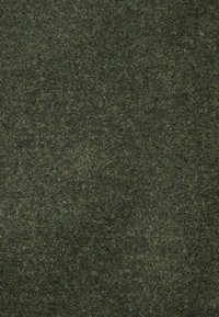 Tissu texturé vert foncé avec une surface dense et légèrement duveteuse. Le matériau présente des variations subtiles de teinte et une apparence douce et naturelle.