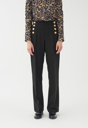 Schwarze maßgeschneiderte Hose mit hoher Taille, ausgestattet mit großen goldenen Knöpfen auf der Vorderseite und einem glatten, strukturierten Stoff.