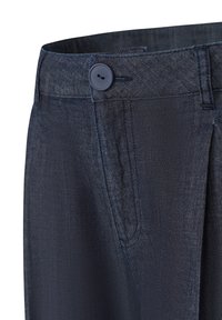 Dunkelblaue, strukturierte Stoffhose mit Knopfverschluss, seitlichen Taschen und tailliertem Schnitt. Fokus auf das Detail des Bunds.